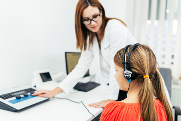 Young girl at medical examination or hearing aid checkup in otolaryngologist's office