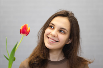 Beautiful girl in the brown dress with flowers tulips in hands on a light background	