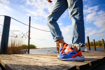 legs with jeans on river pier , sport legs , sport shoes 