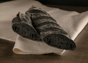 Unusual black baguette on a white napkin, lying on the table