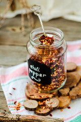 Crushed Red pepper flakes in a shaker on a wooden table.Selective focus.