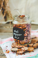 Crushed Red pepper flakes in a shaker on a wooden table.Selective focus.Toning.