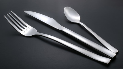knife, fork and teaspoon on black background