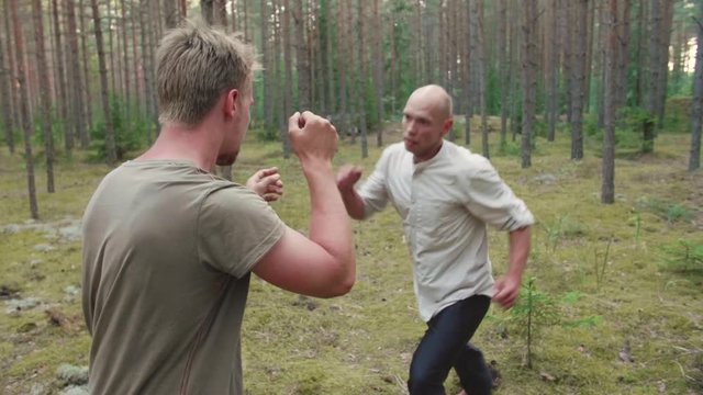 Martial artists friendly sparring on in the forest in slow motion, 50 fps.