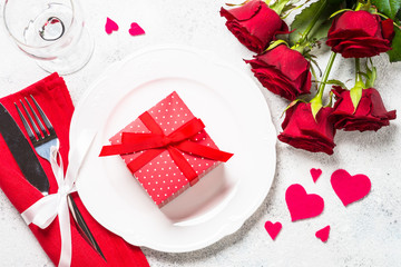 Valentines day table setting with plate, roses and present. 