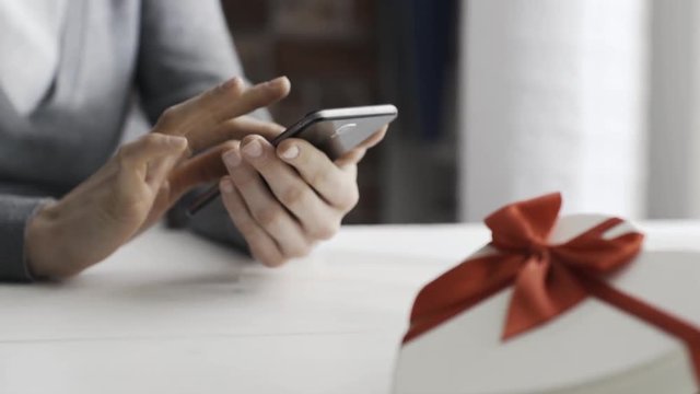 Woman receiving a gift from her boyfriend and texting on her phone