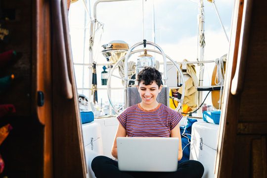 Smiling woman using laptop in boat