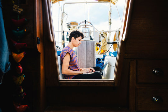 Side view of woman using laptop in boat