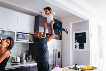 Smiling parents playing with children in kitchen at home