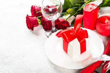 Romantic holiday table setting with plate, roses and present.