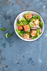 Healthy lunch salad with baked salmon fish, fresh radish, lettuce and lime. Top view