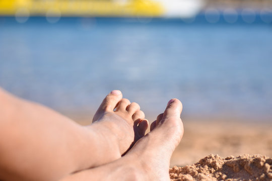 Children feet on the sea beach, close-up, copy space