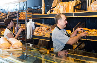 staff offering fresh baguettes and buns in bakery