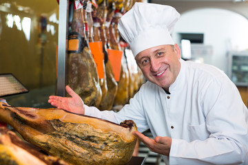 Positive mature man working with iberian jamon