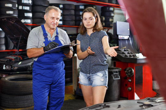 Mechanic with client recording workslist on car repair