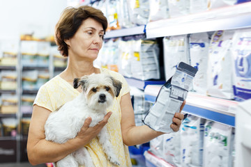 Smiling woman choosing dog food for her puppy
