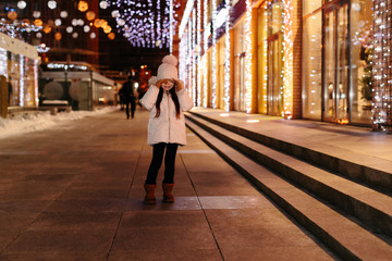 Cute scared lost little girl in a big city in the evening in winter