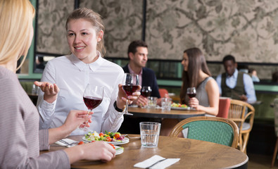 Fototapeta na wymiar Cheerful woman with female friend in restaurant