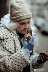 Sad homeless woman holding bread in her hand