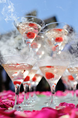 A slide of champagne with dry ice and smoke at the solemn event. Pyramid of glasses with alcohol and cherries.