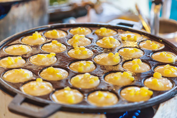 Khanom Khrok (coconut rice pancake), Traditional Thai Pudding Pancake Dessert, prepared by mixing rice flour, sugar, and coconut milk to form dough cooked in heating mantle (hot indented frying pan)