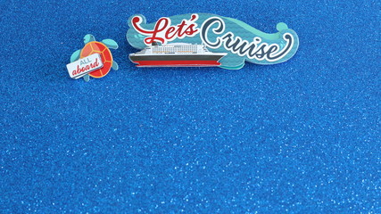 Lets cruise written on a banner with a cruise ship at sea written on a button and all aboard...