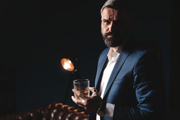 Degustation, tasting. Man with beard holds glass of brandy. Tasting and degustation concept. Bearded businessman in elegant suit with glass of whiskey