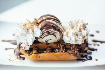 Waffle with chocolate and ice cream on white plate 