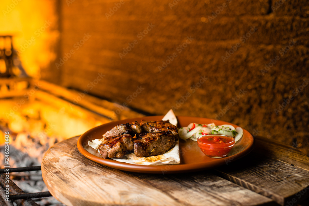 Wall mural shashlik on pita bread in a clay plate, against the background of barbecue