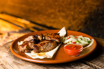 shashlik on pita bread in a clay plate, against the background of barbecue