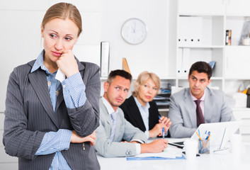 Business woman crying in office with working colleagues