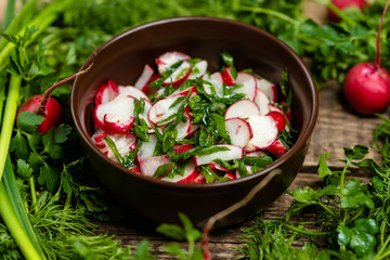 radish salad with green onions in a clay plate on a wooden board