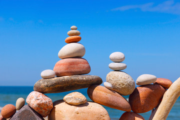 Rock zen pyramid of colorful pebbles on a beach on the background of the sea.