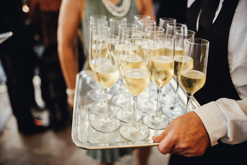 Waiter carries glasses with cold champagne