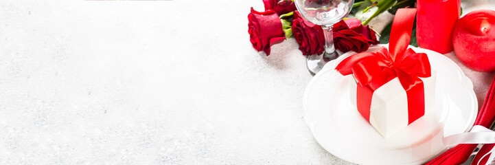 Romantic holiday table setting with plate, roses and present.