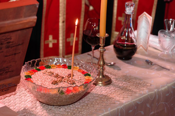 Orthodox cooked wheat in a bowl with walnuts next to candlestick and glass of red wine  prepared for a holy day