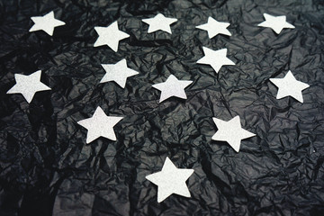 Diy background of silver stars over a crumpled black paper background 