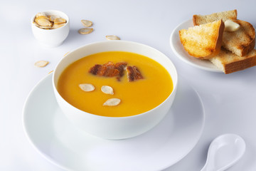 A bowl of spicy squash soup with bacon and toasts. High Key. Selective focus.