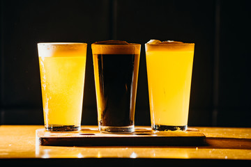 Glasses of light and dark beer in a pub. Dark background.