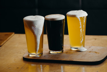 Glasses of light and dark beer in a pub. Dark background.