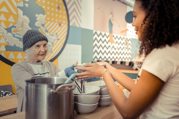 Positive senior woman taking her hot soup