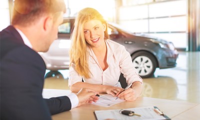 Happy woman with car dealer in auto show or salon