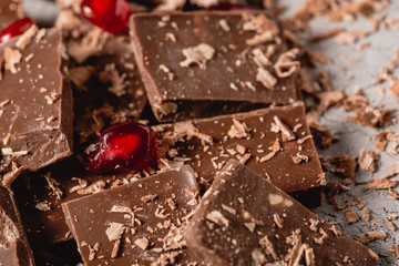 Broken chocolate pieces and chocolate powder, chocolate with hazelnut, chocolate and red pomegranate on beton background with copy paste place