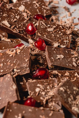 Broken chocolate pieces and chocolate powder, chocolate with hazelnut, chocolate and red pomegranate on beton background with copy paste place