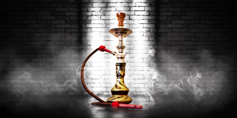 Hookah smoking on the background of an empty brick wall and concrete floor. Spotlight, neon light,...