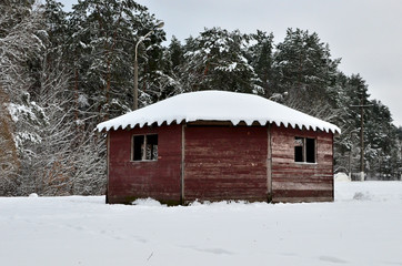 Wooden arbor covered with snow on the background of winter nature in the forest. Hunter's house.