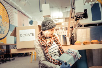 Poor aged woman looking at the gift box