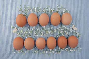   Eggs nature in two rows, in between Gypsophila and Easter bunnies on woven tablecloth