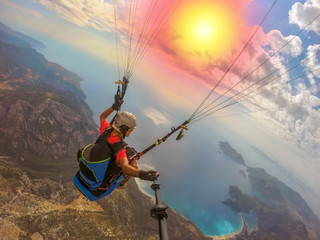 Paraglider tandem flying over the sea with blue water and mountains in bright sunny day. Aerial view of paraglider and Blue Lagoon in Oludeniz, Turkey. Extreme sport. Landscape