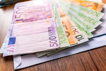 Euro banknotes in salary envelope. Open envelope with money banknotes on table. White envelope with Euro bills. Closeup on Envelope full of euro cash. Euro money currency. International monetary